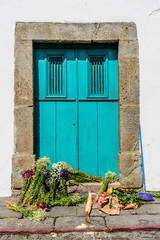 Broom & bundles of flowers strewn on doorstep of turquoise door, Guatemala, Central America