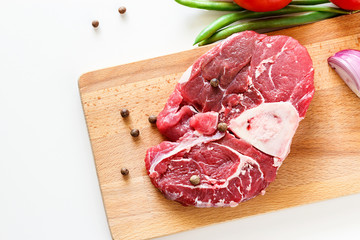 Raw meat beef steak with fresh vegetable on wooden cutting board. Top view.