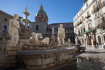 Fontana Pretoria, Palermo. Group of white marble statues part of the Pretoria Fountain of Palermo. Statues of naked woman and man, and Poseidon laying down. With church dome at background.