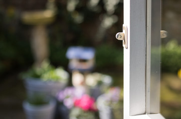 Open window onto a garden on a sunny day. Good morning and have a happy day! It is a view from inside on the blurred background of blossom nature. 