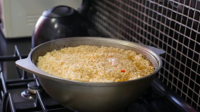 Cooking rice in metal pan on hotplate in kitchen