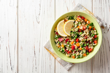 Fresh salad with bulgur and vegetables on white wooden table
