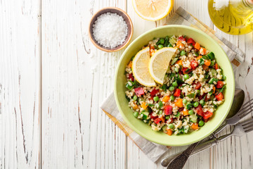 Fresh salad with bulgur and vegetables on white wooden table