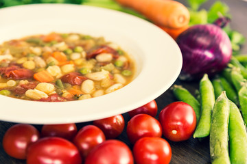 A close up of vegetable soup with tomatoes, carrots, celery, onions and other various vegetables