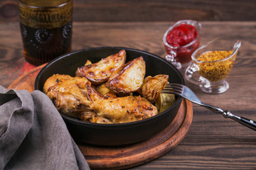 Fried chicken legs with fried potatoes in pan