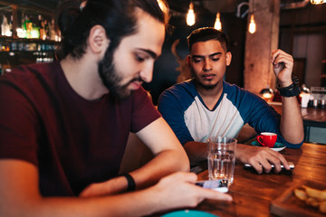 Social network addiction. Two mixed race friends using smartphones in restaurant instead of communicating