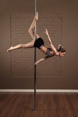 Sports girl doing acrobatics on a pole