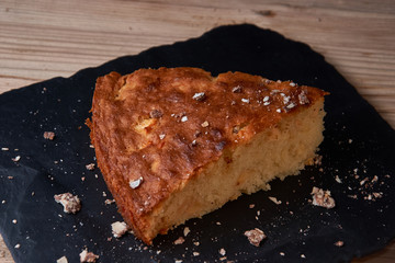 Apple pie tart on shale board with raisins, nuts and cinnamon is a vintage wooden background texture. Rustic style