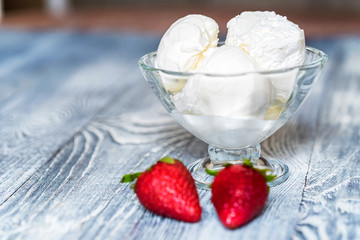 Tasty vanilla ice cream in bowl and strawberries