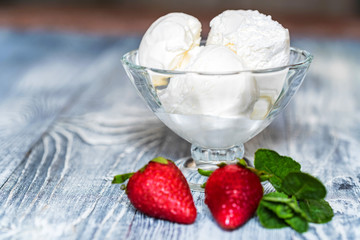 Tasty vanilla ice cream in bowl and strawberries