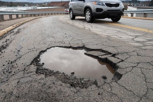 Pothole in road with broken asphalt after spring thaw