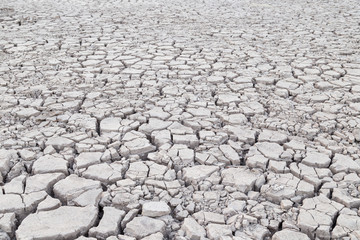 View of cracked and parched gray soil ground after drought