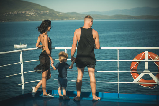 Family travelling on cruise ship on sunny day. Family with cute son on summer vacation. Father, mother and child stand on deck of cruise liner with sea waves on background. Family rest concept.
