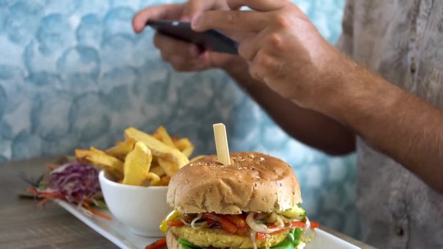 Man Taking Mobile Pictures of Burger with French Fries. Social Media Lifestyle
