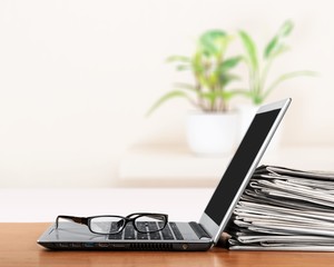Laptop and black glasses on table