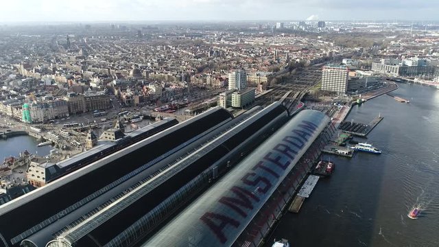 Aerial footage moving backwards away from Amsterdam Centraal the largest railway station of Amsterdam Netherlands and major national railway hub and the most visited national heritage site of Holland