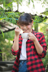 asian beautiful woman drinking hot coffee or tea in the green garden