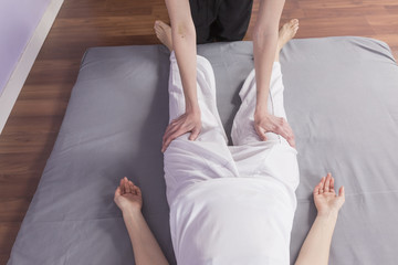 Young woman lying while enjoying stretching and the acupressure techniques of traditional Thai...