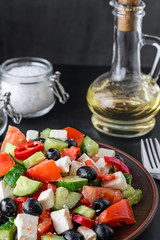 Greek dietary salad and olive oil on dark background