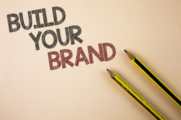 Writing note showing  Build Your Brand. Business photo showcasing create your own logo slogan Model Advertising E Marketing written on Plain background Pencils next to it.