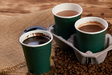 Three cardboard coffee cups. Take away green paper cups with coffee beans and hot chocolate drink...