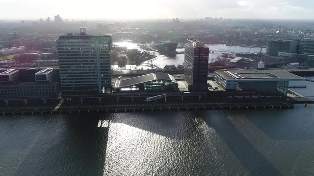Urban aerial Amsterdam city center moving towards business buildings showing two tall buildings located at Amsterdam docks in background showing further Amsterdam downtown and NEMO science museum 4k
