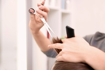 Professional female hairdresser working with client in salon