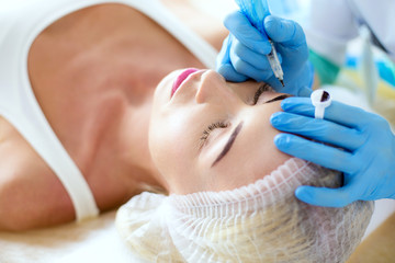 Permanent makeup for eyebrows. Closeup of beautiful woman with thick brows in beauty salon.