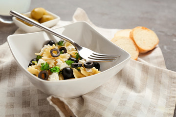 Tasty pasta salad with black olives on table