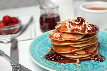 Delicious pancakes with jam and nuts on plate served for breakfast , closeup