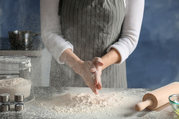 Woman sprinkling flour over table in kitchen
