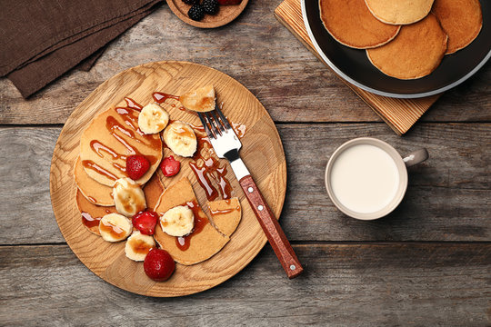 Delicious pancakes with strawberry, banana and syrup served for breakfast on table