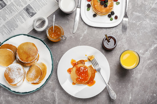 Delicious pancakes with jam and glass of juice served for breakfast on table