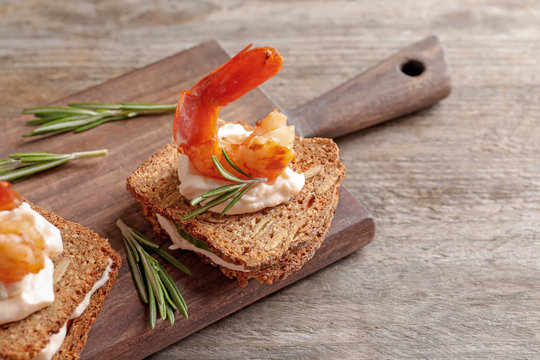 Delicious small sandwiches with shrimps on wooden board