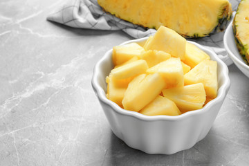 Bowl with fresh sliced pineapple on table