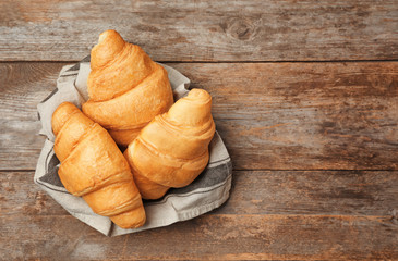 Tasty croissants on wooden background, top view