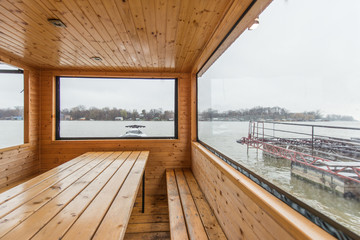 Sauna with sitting place and table, big bright window view on river