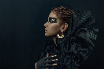 conceptual portrait of beautiful fashion look woman dark make up with gold