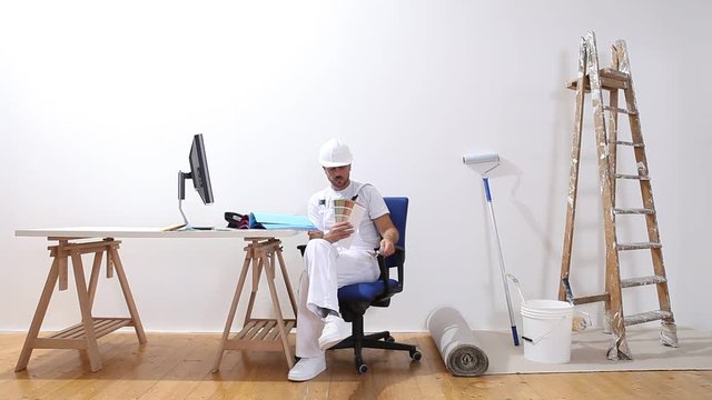 house painter man with a computer and magnifying glass looks at color samples and search the internet, e-commerce and shop paint colors concept,