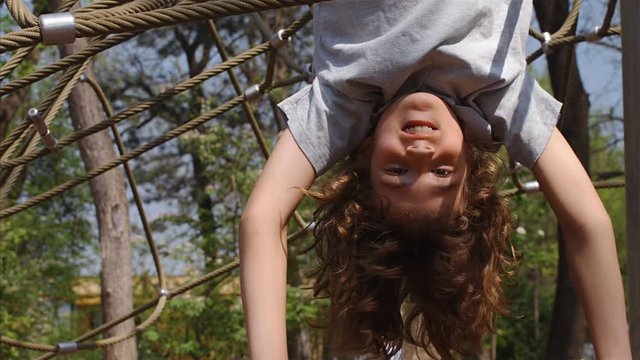 Slow motion of 10 years old boy hanging upside down on jungle gym, 4k