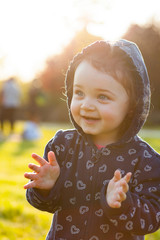 Little baby girl plays in the park in backlight.