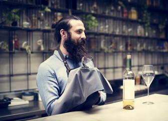 A male bartender cleaning wine glass  