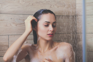 Naklejka premium Young beautyful woman under shower in bathroom.