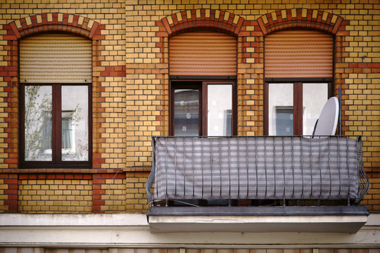 Balkon mit Gusseisengeländer / Die Fassade eines alten Wohngebäudes mit einer Klinkerfassade und einem nostalgischen Balkon.