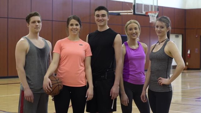 Young men and women standing on a basketball quart