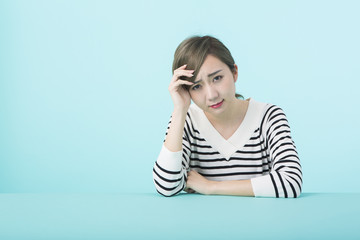 額に手を当てて眉間に皺を寄せる若い女性