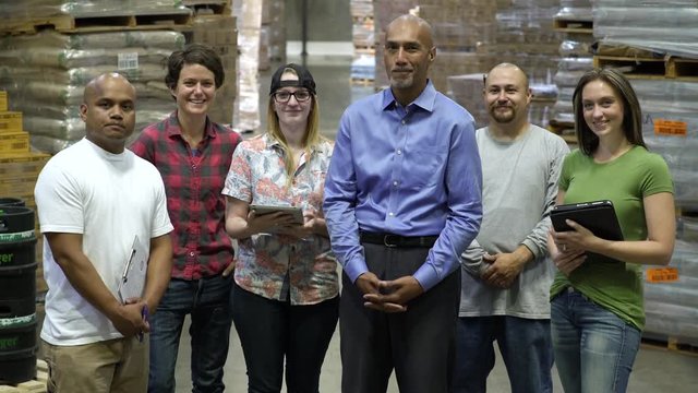 Female and male work team, standing in a row, smiling at camera.
