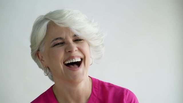 Woman with short hair laughing and nodding, studio shot.