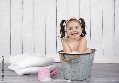 Cute Little Girl In Pink Headband Sits In Bubble Bath In