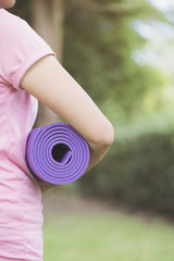 Young woman holding a yoga mat in exercise class for a sport and healthy concept